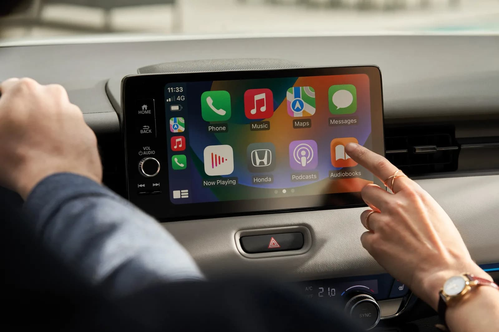 Mâna unui șofer atingând ecranul tactil cu interfața Apple CarPlay