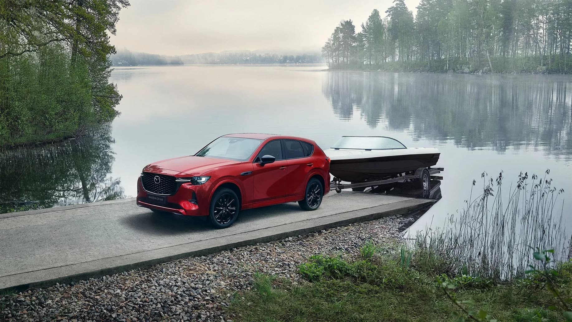 Mazda CX-60 — CX-60 roșie coborând o barcă pe remorcă, la o rampă de lac