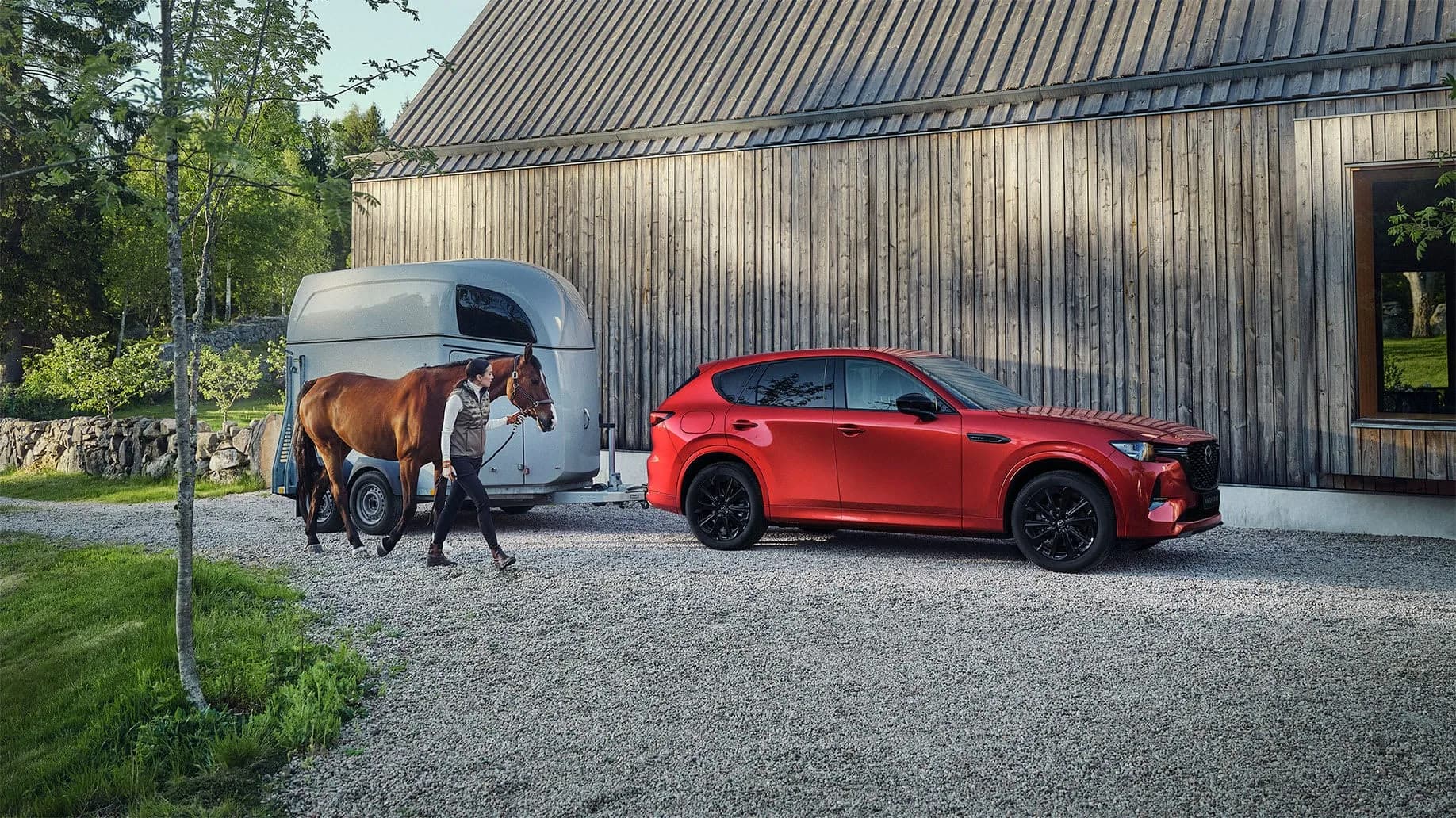 Mazda CX-60 — CX-60 roșie lângă o remorcă pentru cai, cu un cal condus de căpăstru