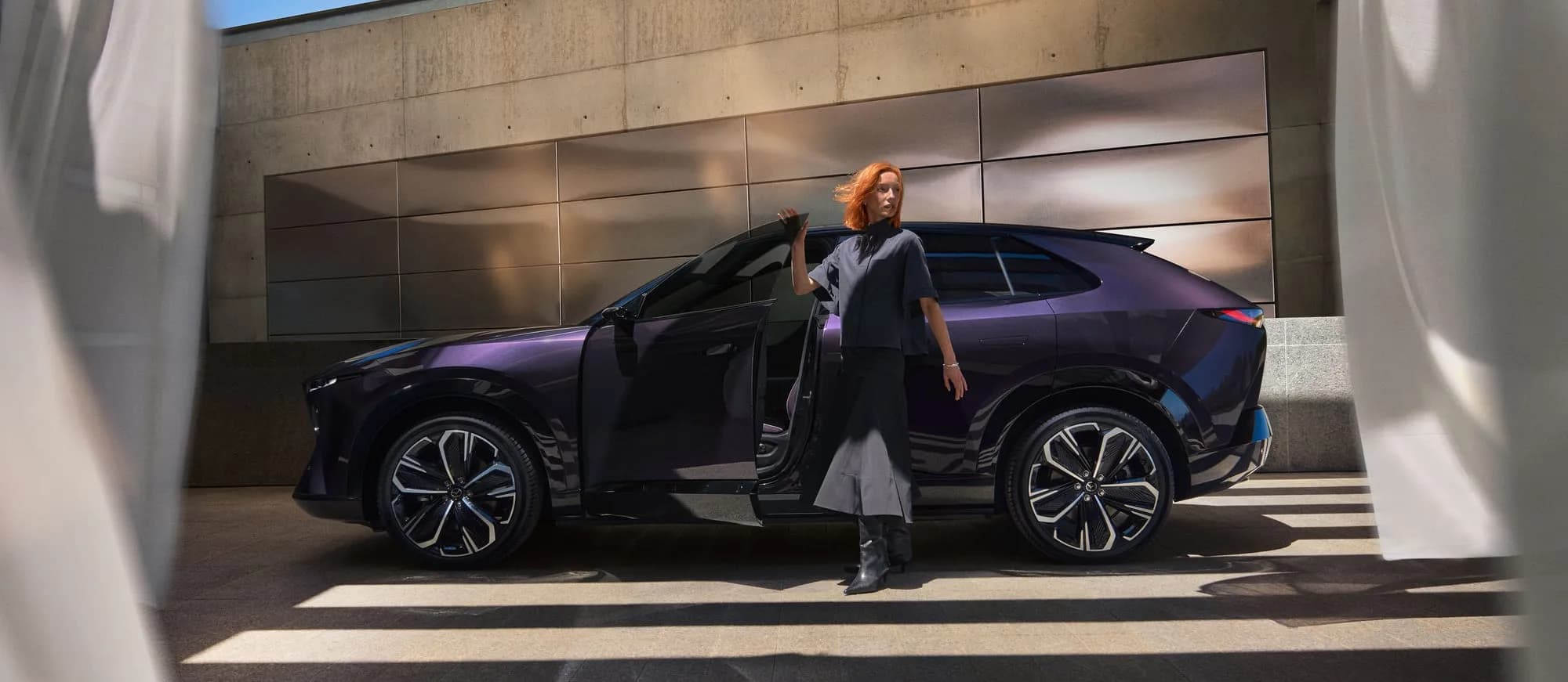 Mazda CX-6e — o femeie coboară din mașină, cu portiera fără ramă deschisă