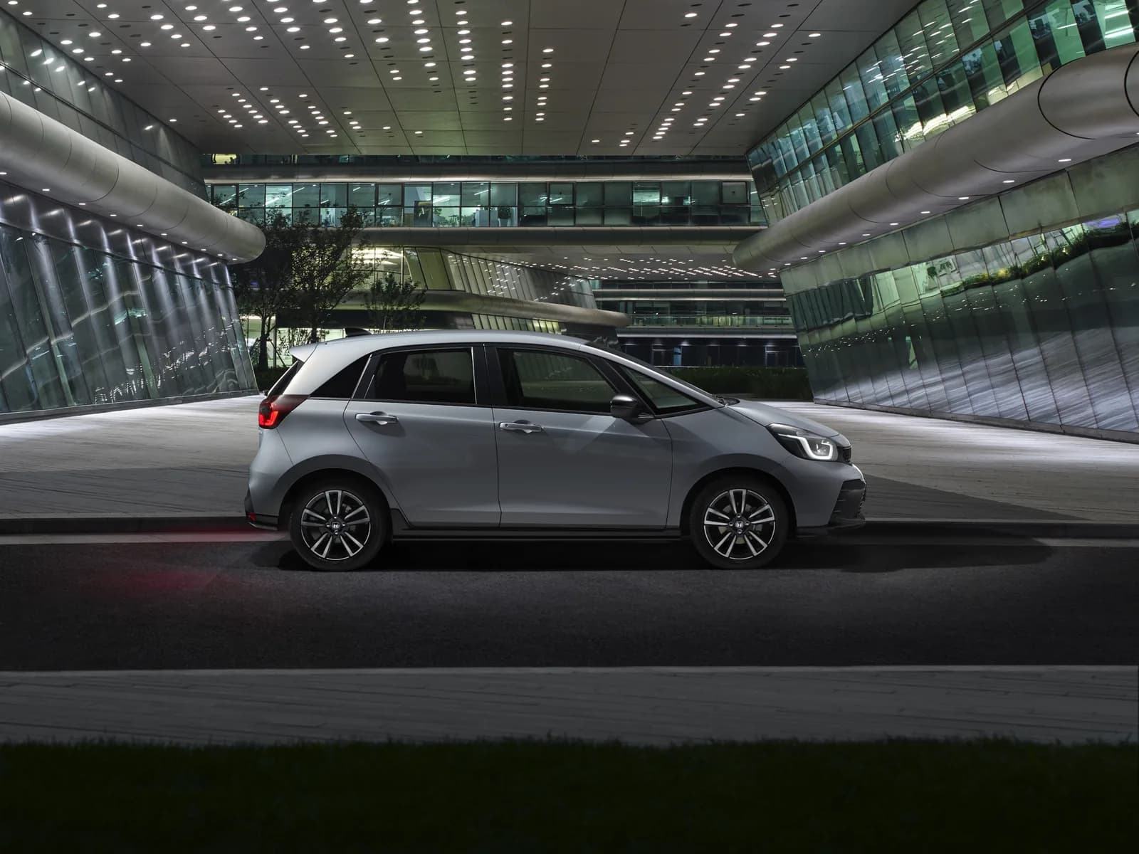 Honda Jazz gri, văzută din profil, pe o platformă lângă o clădire de birouri