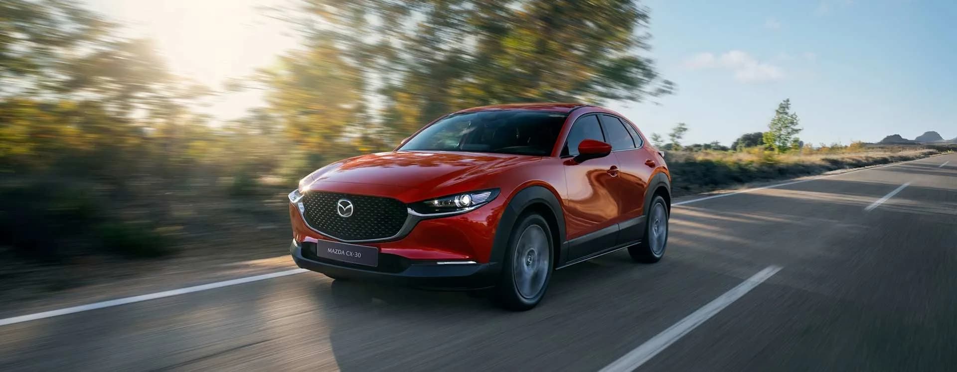 Mazda CX-30 roșie în mers pe un drum deschis