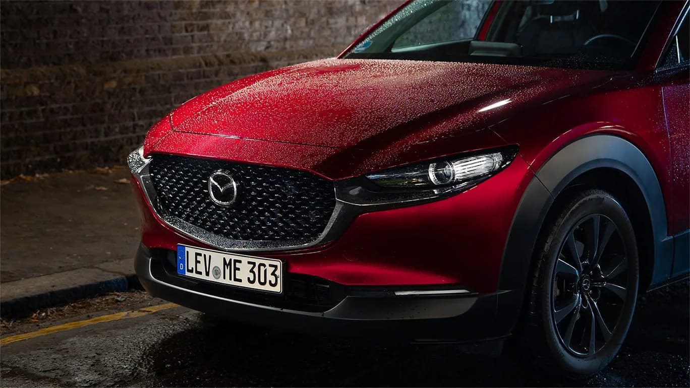 Mazda CX-30 — partea din față a mașinii, pe ploaie, cu farurile aprinse