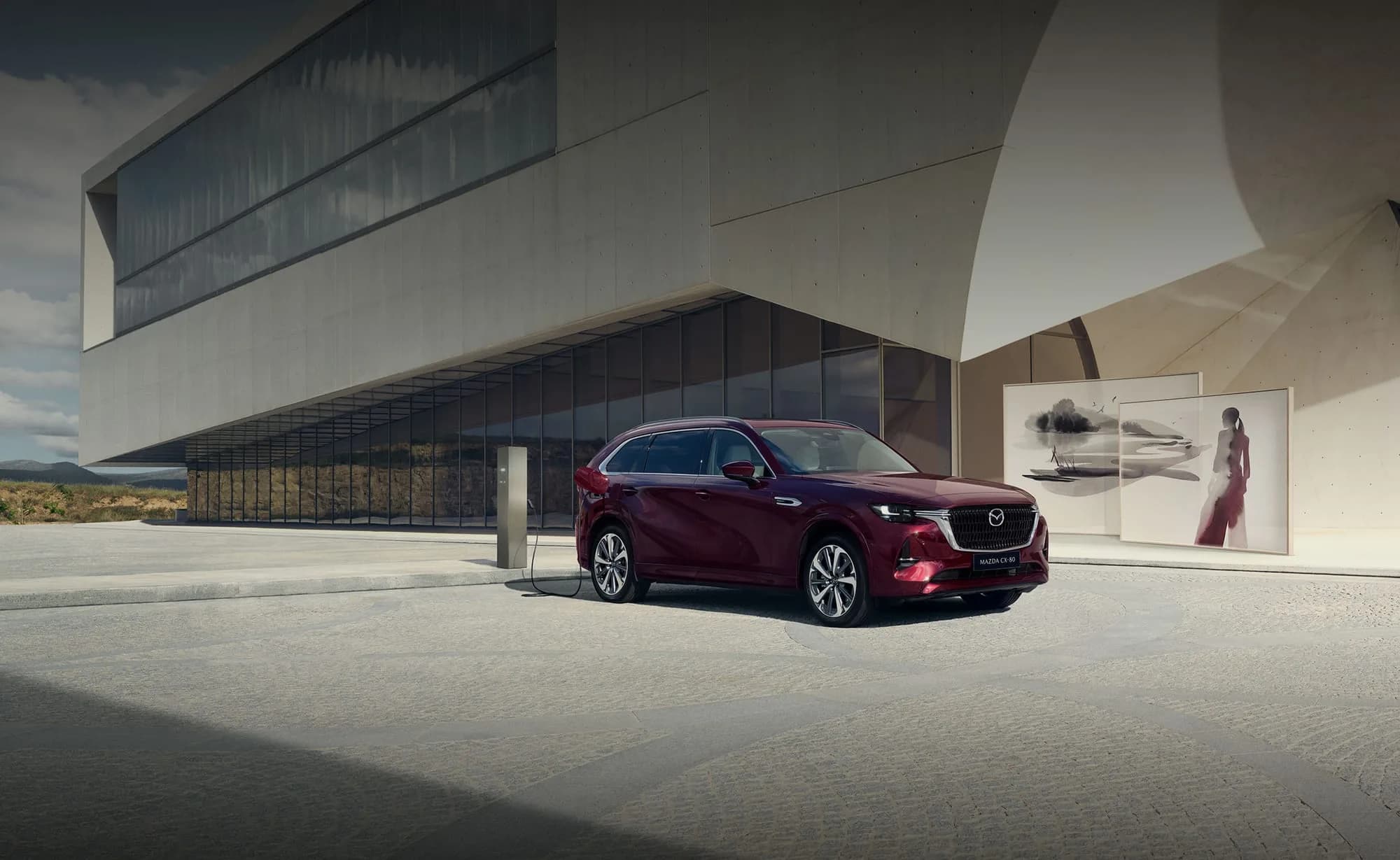 Mazda CX-80 — CX-80 parcat lângă o clădire modernă, din lateral