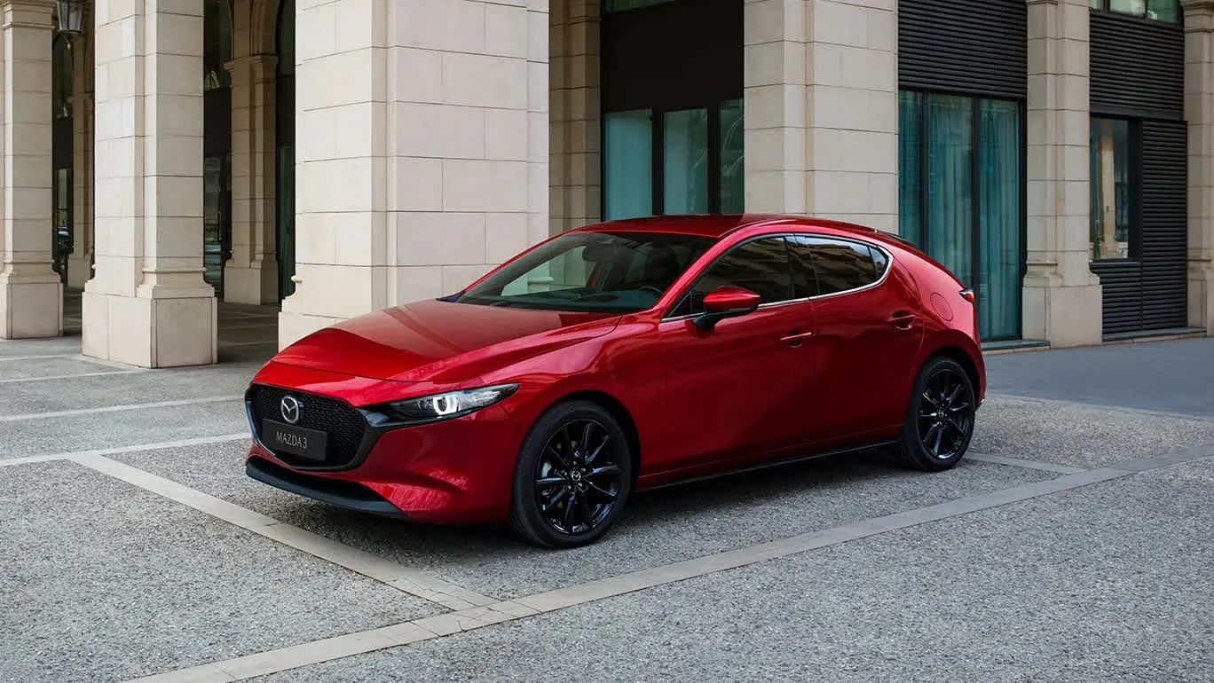 Mazda3 — hatchback roșu parcat lângă o clădire clasică